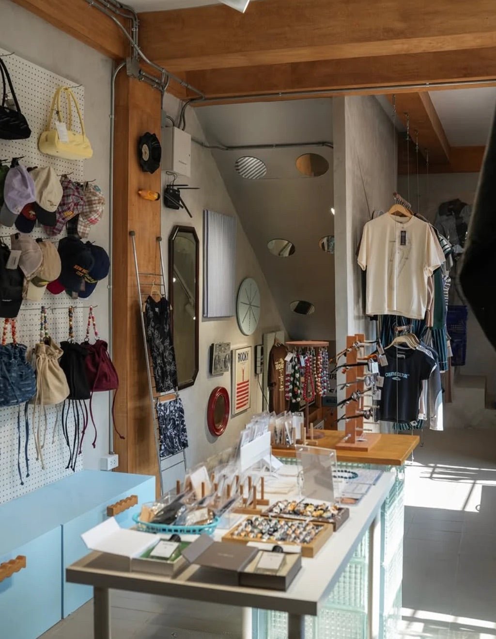 Songwat interior with exposed wooden beams, caps and bags on a pegboard, and a display table